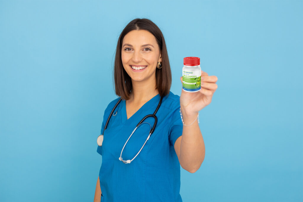 Healthcare worker in blue scrubs holding a medication bottle