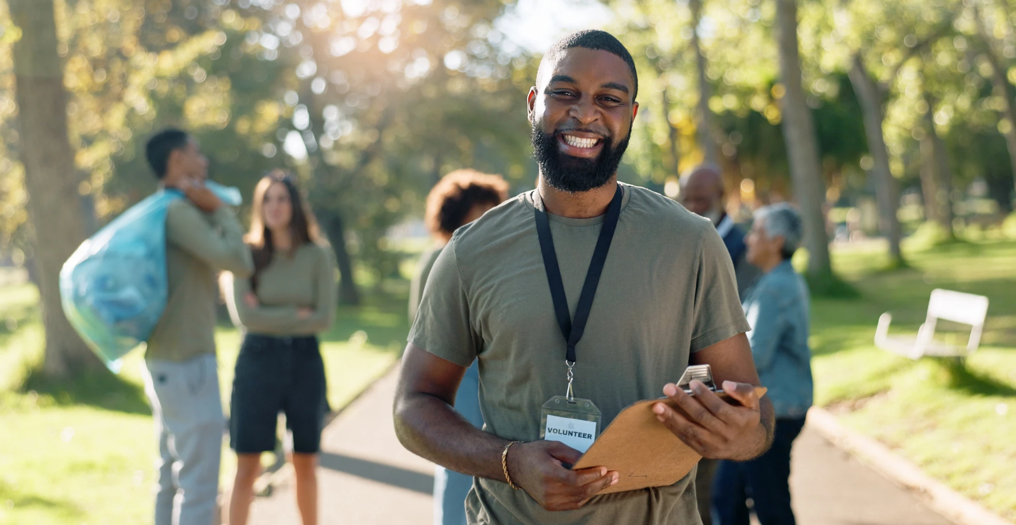 Healthcare professional holding clipboard talking to colleagues in sunny park setting