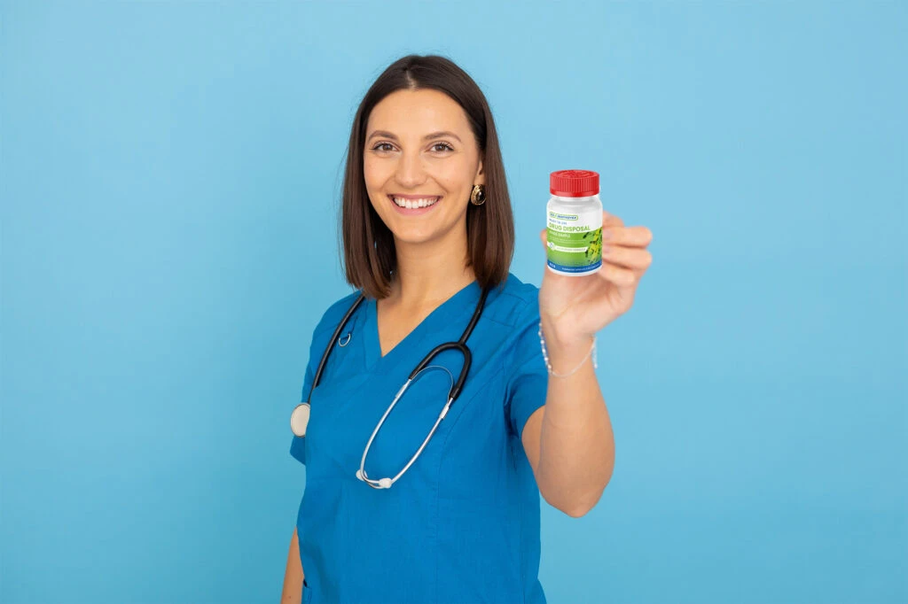 Healthcare worker in blue scrubs holding a medication bottle